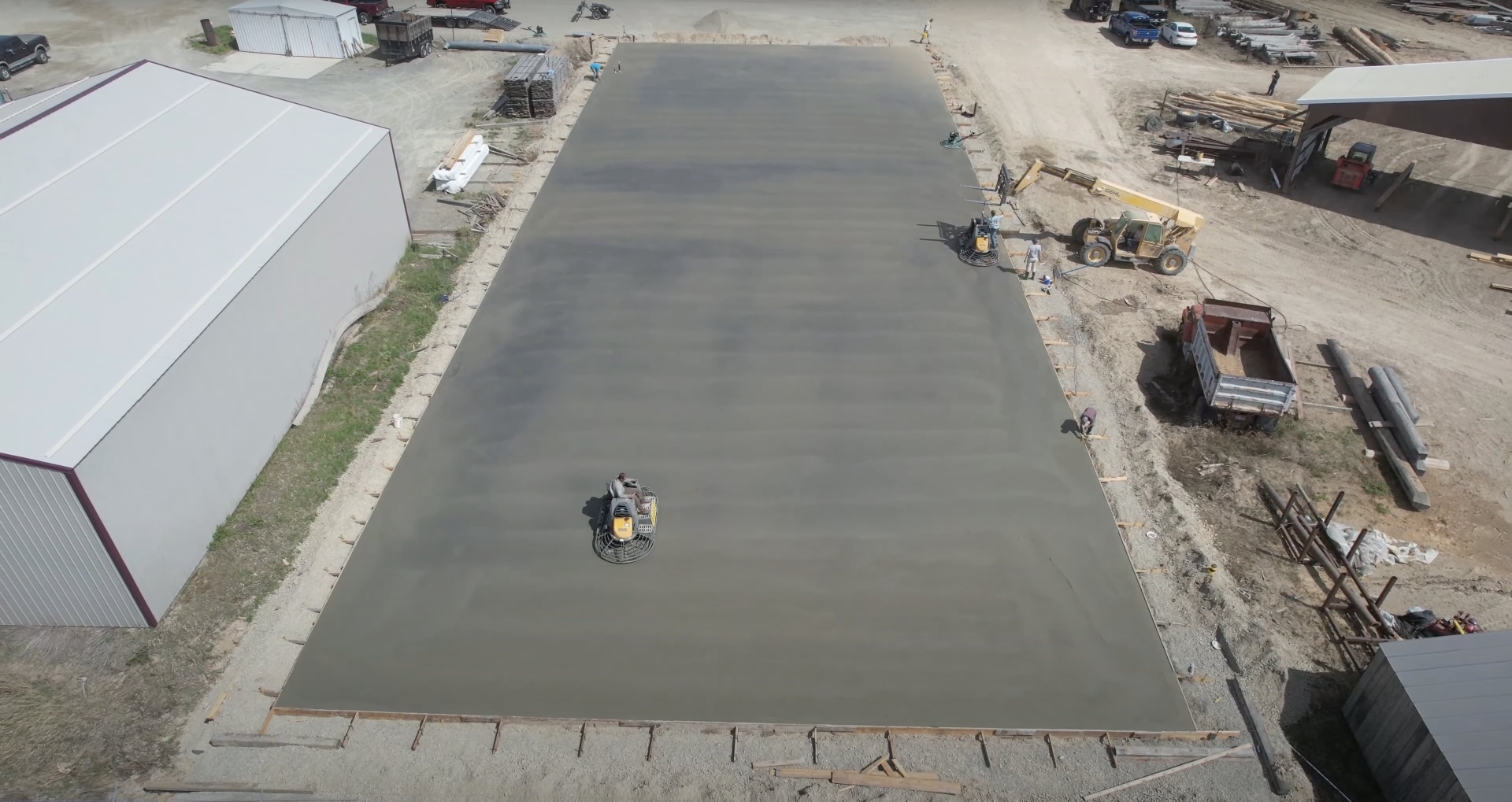 Large-scale concrete slab installation showing professional construction techniques and equipment Aerial view of large concrete slab being poured and finished with professional equipment on construction site